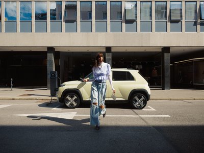 Eine junge Frau überquert die Straße vor einem modernen Hyundai SUV – Szene aus der Hyundai Neuwagenübersicht mit urbanem Lifestyle-Flair.