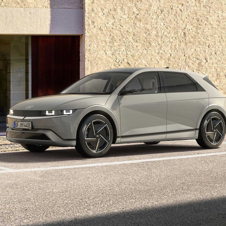 Weißer Hyundai KONA Elektro vor einem modernen Gebäude mit Personen im Außenbereich